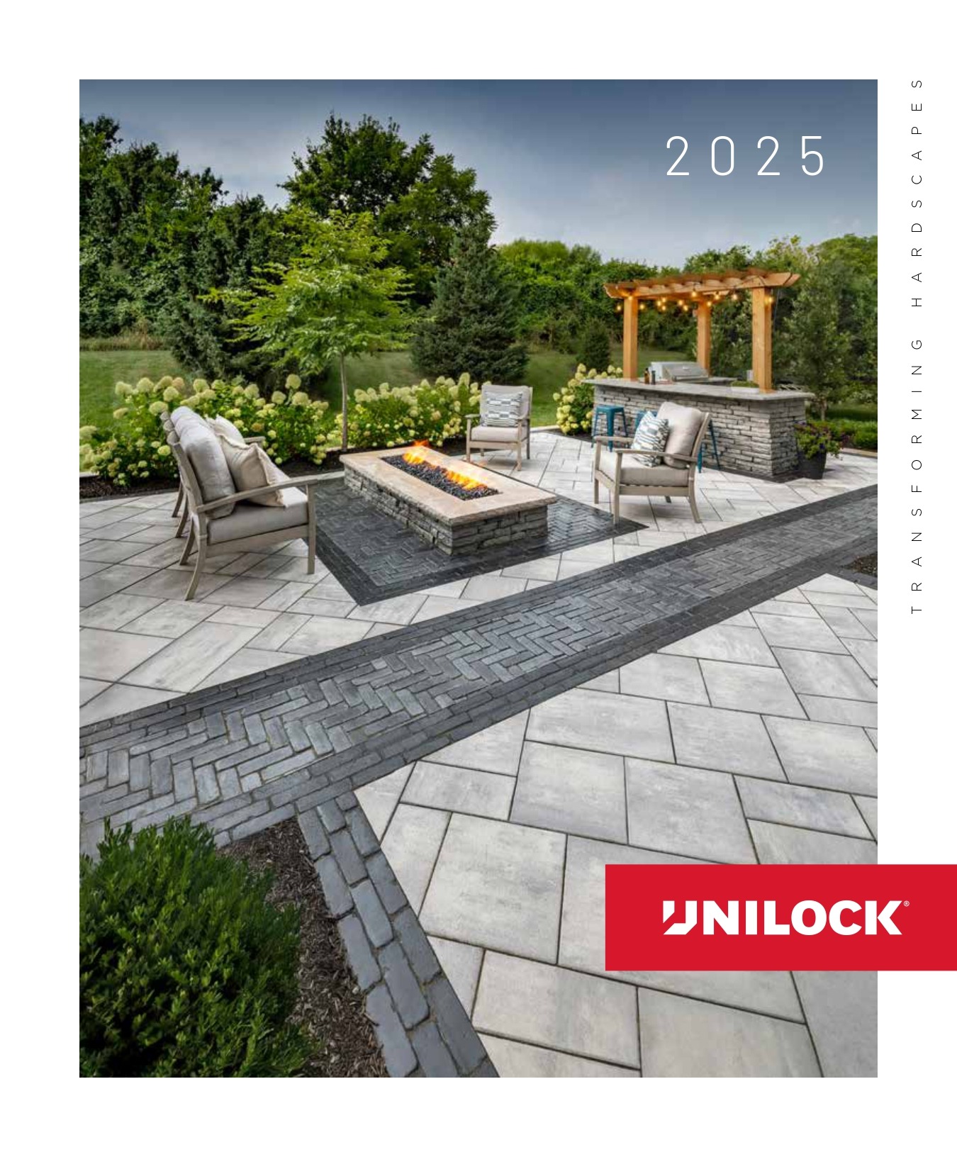 Modern patio with elegant stone flooring, a cozy fire pit, and pergola amid lush greenery. Unilock logo prominently displayed in corner.