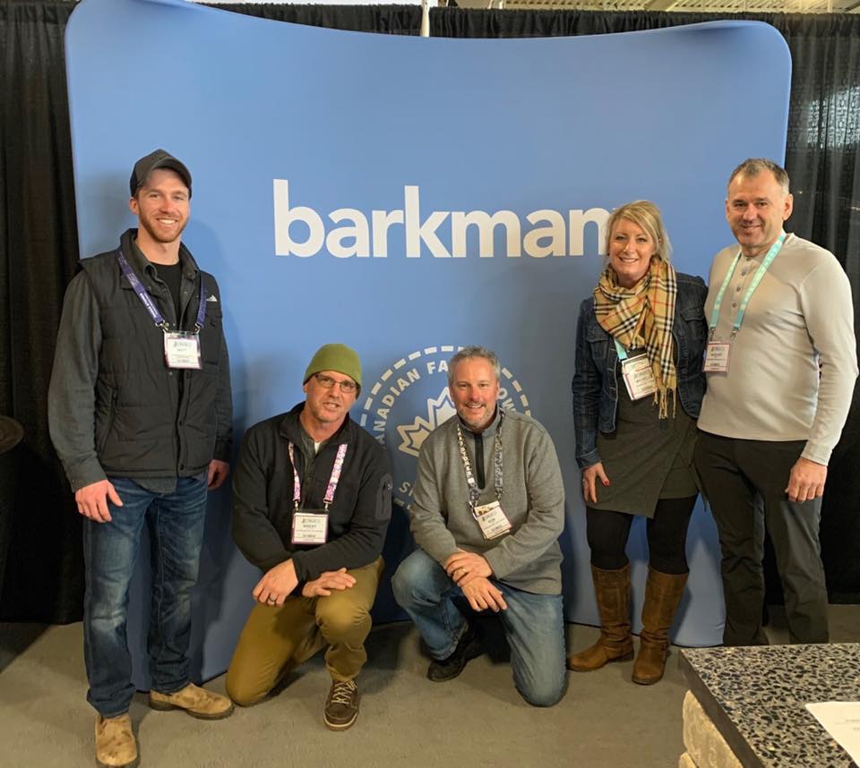 Five people pose at an event, wearing nametags, against a blue backdrop with "barkman" text and a Canadian Farmers' logo.