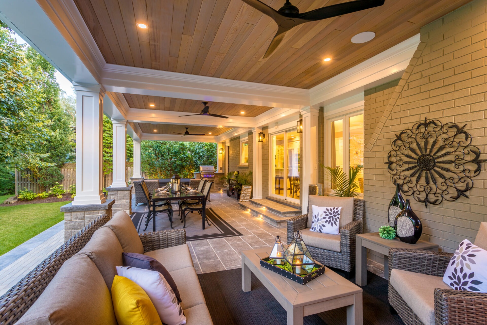 Elegant, covered patio featuring comfortable seating, dining area, decorative lighting, and lush garden view, creating a cozy outdoor living space.