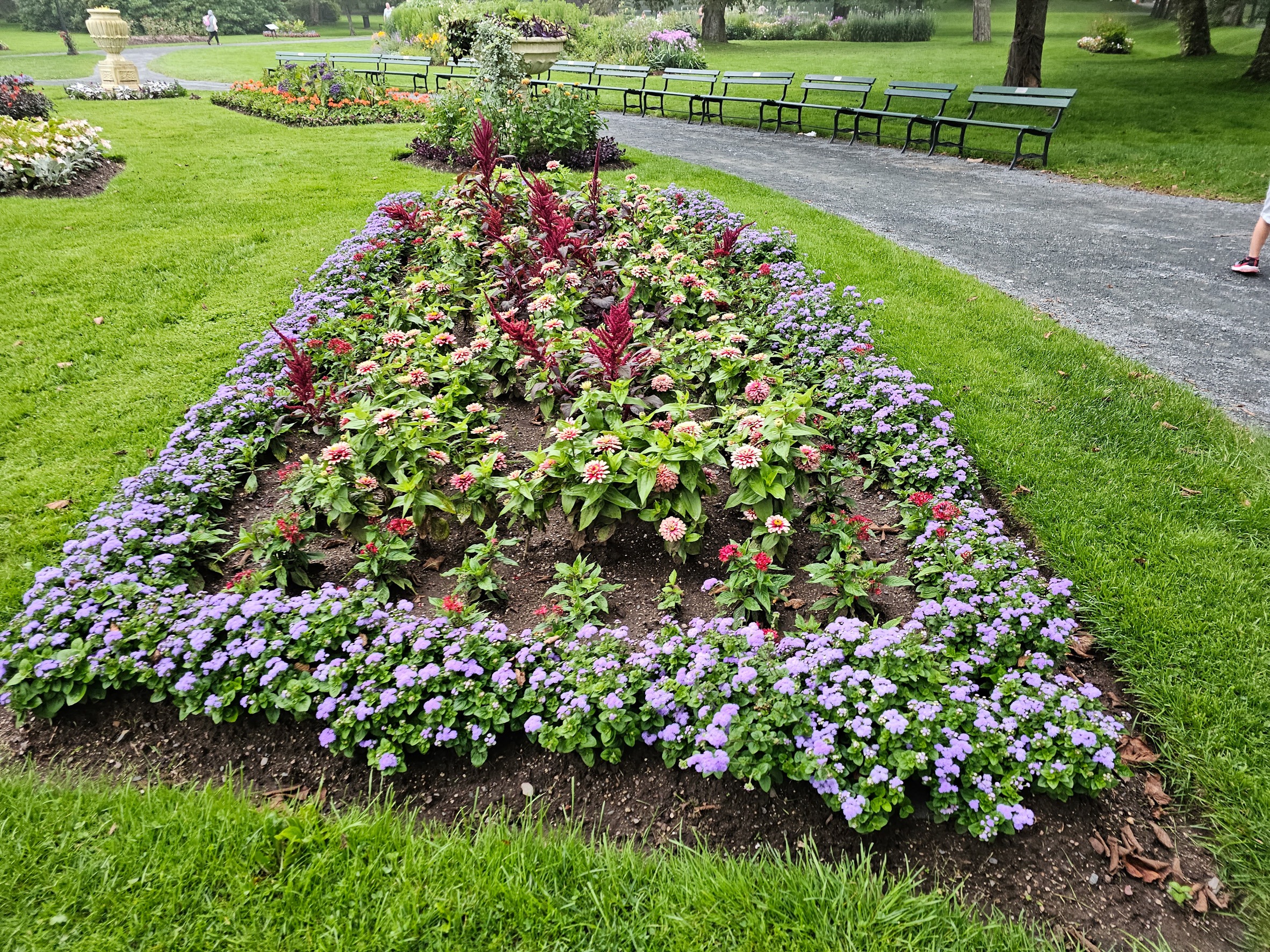 A flower bed laid in a beautiful garden with a road to the side.