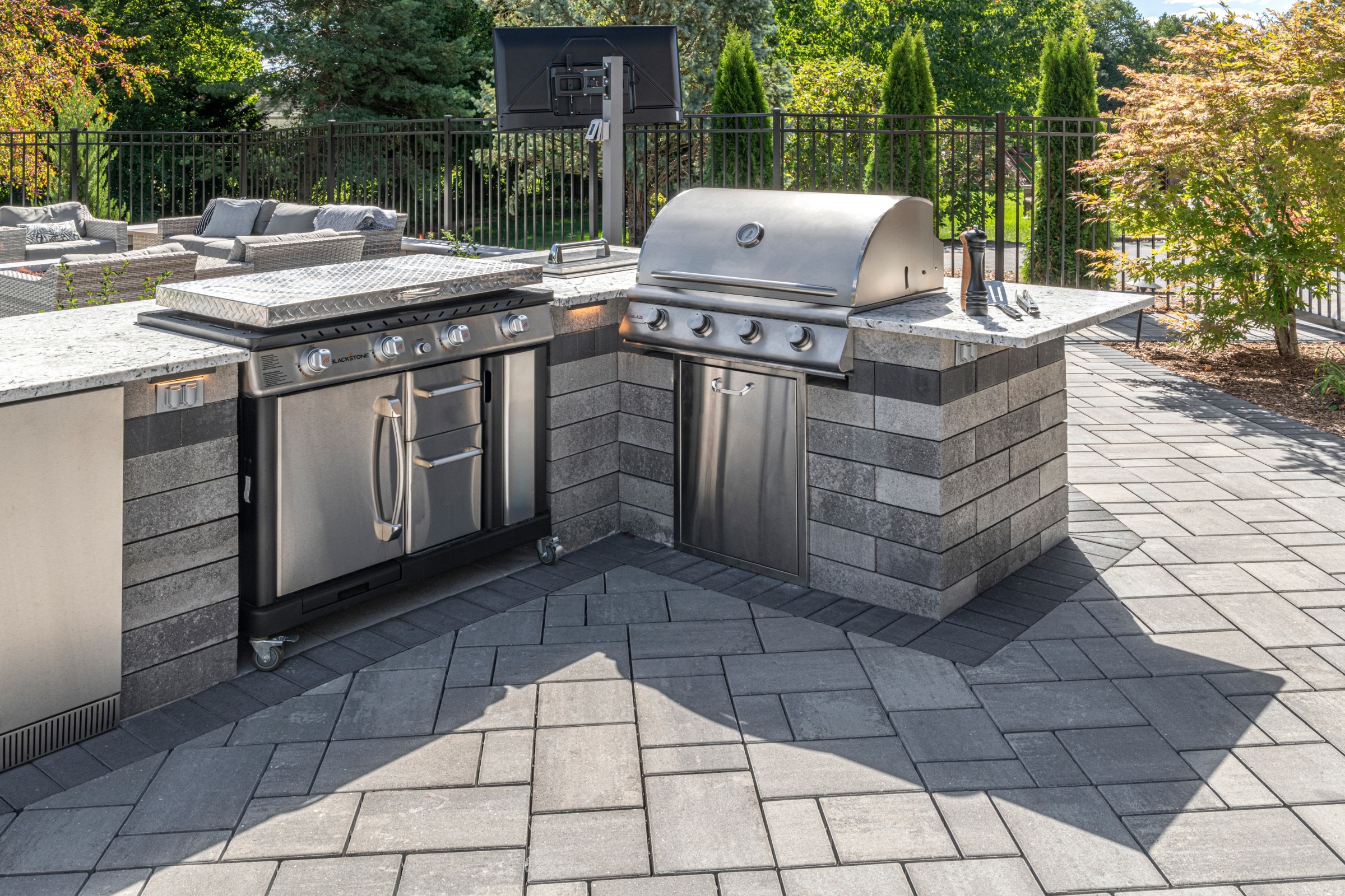 Modern outdoor kitchen with stainless steel grill and stone countertops.