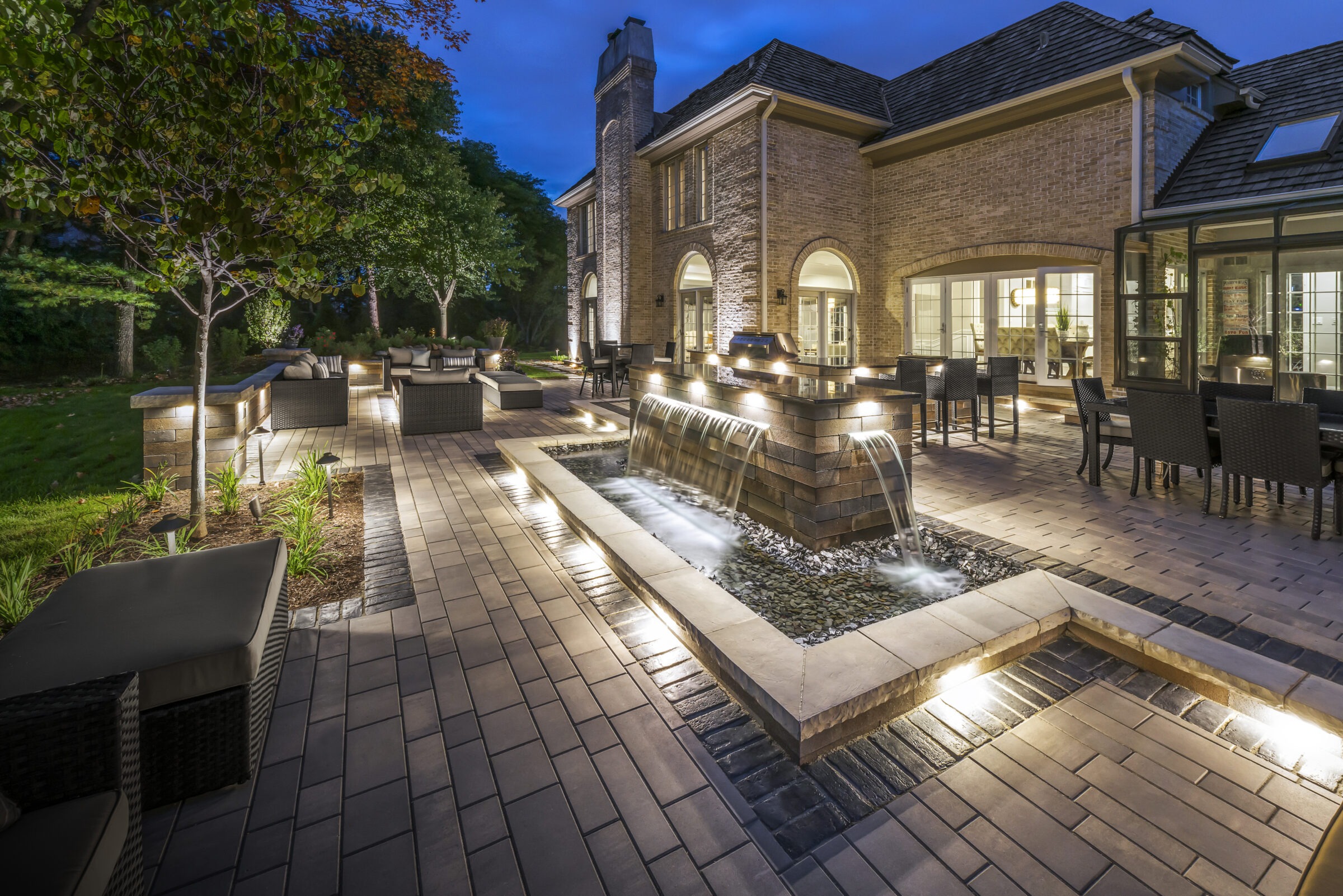 Elegant backyard with stone water feature and landscape lighting.