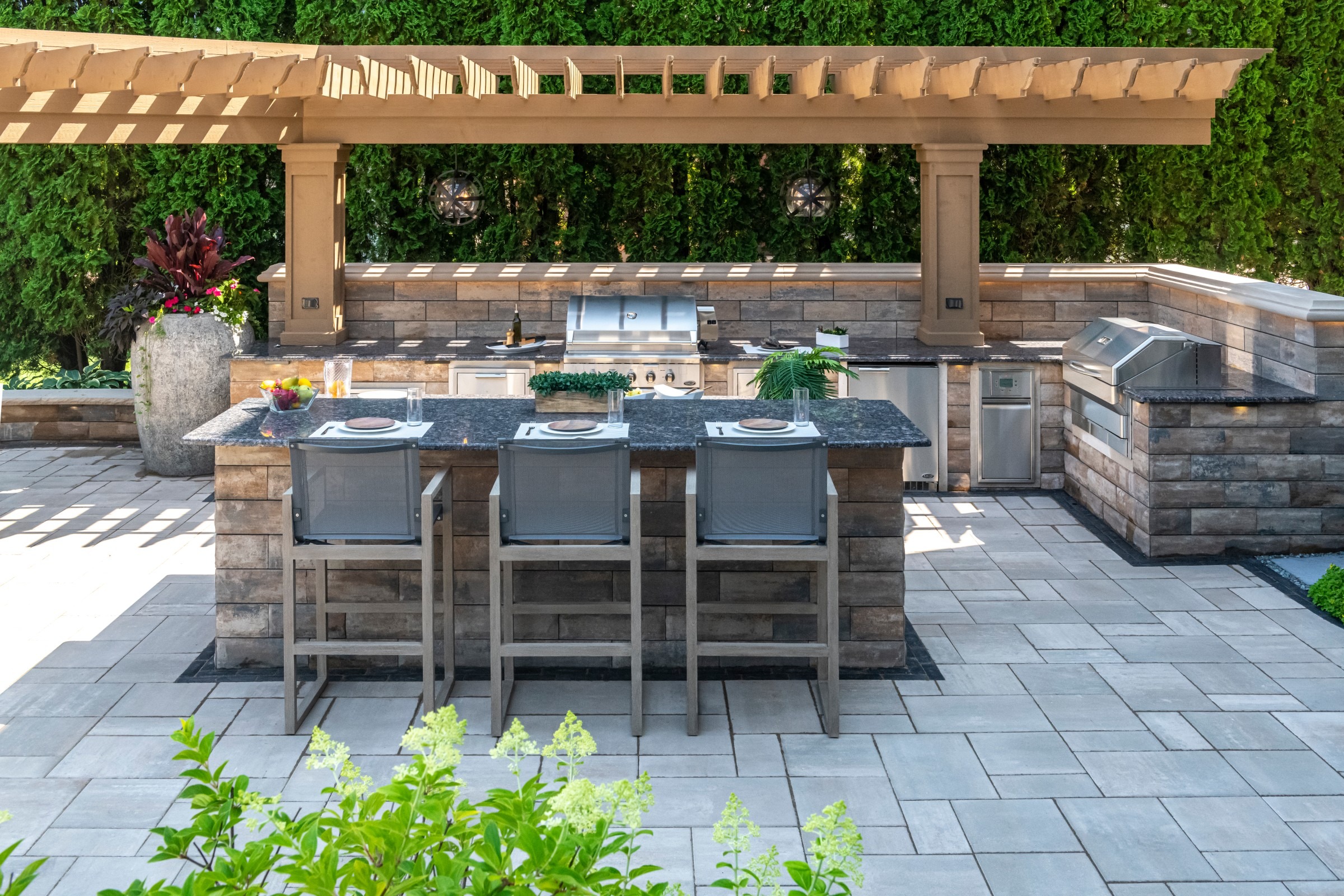 Covered patio outdoor kitchen with bar seating and pergola structure.