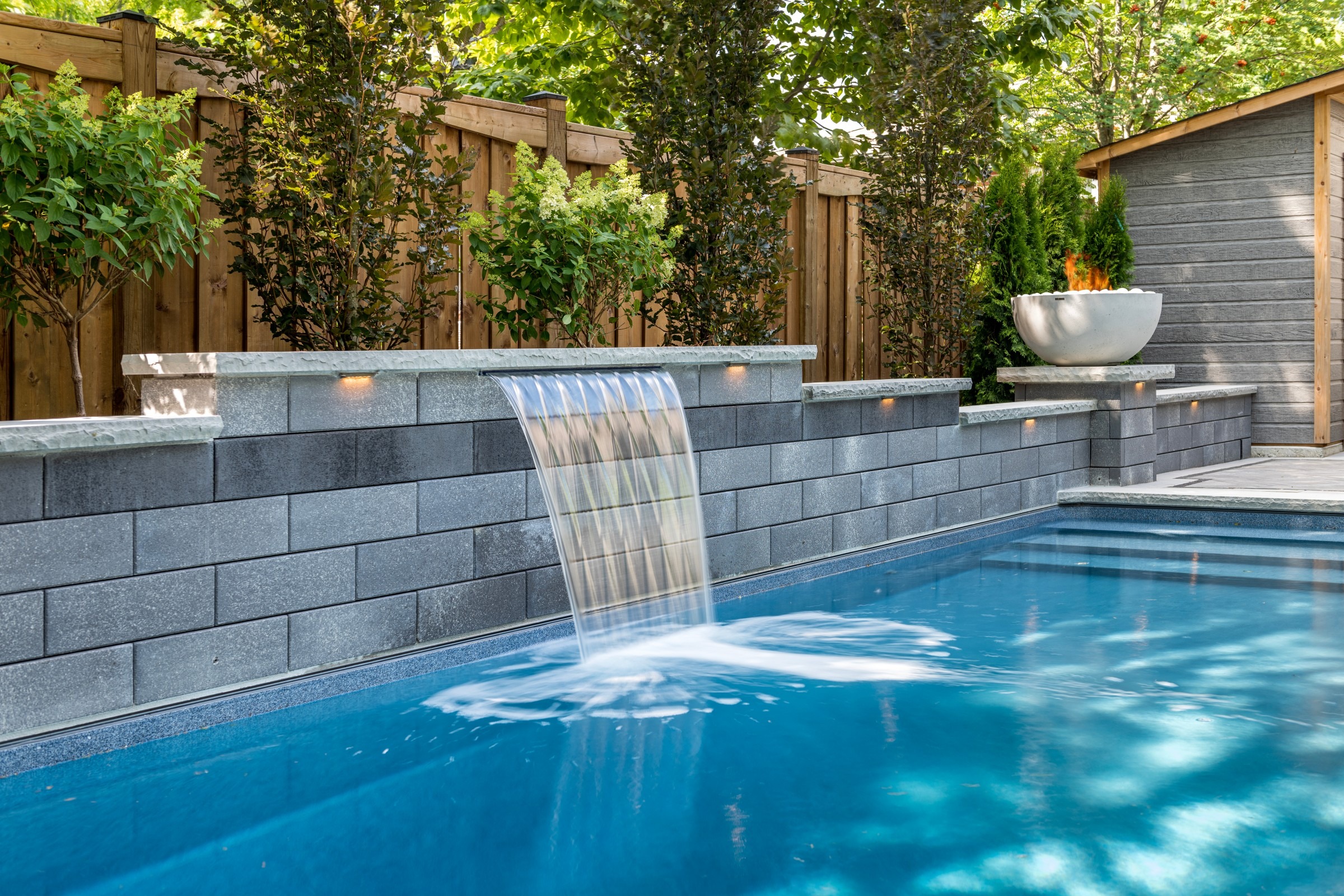 Modern backyard with pool water feature and LED lighting.