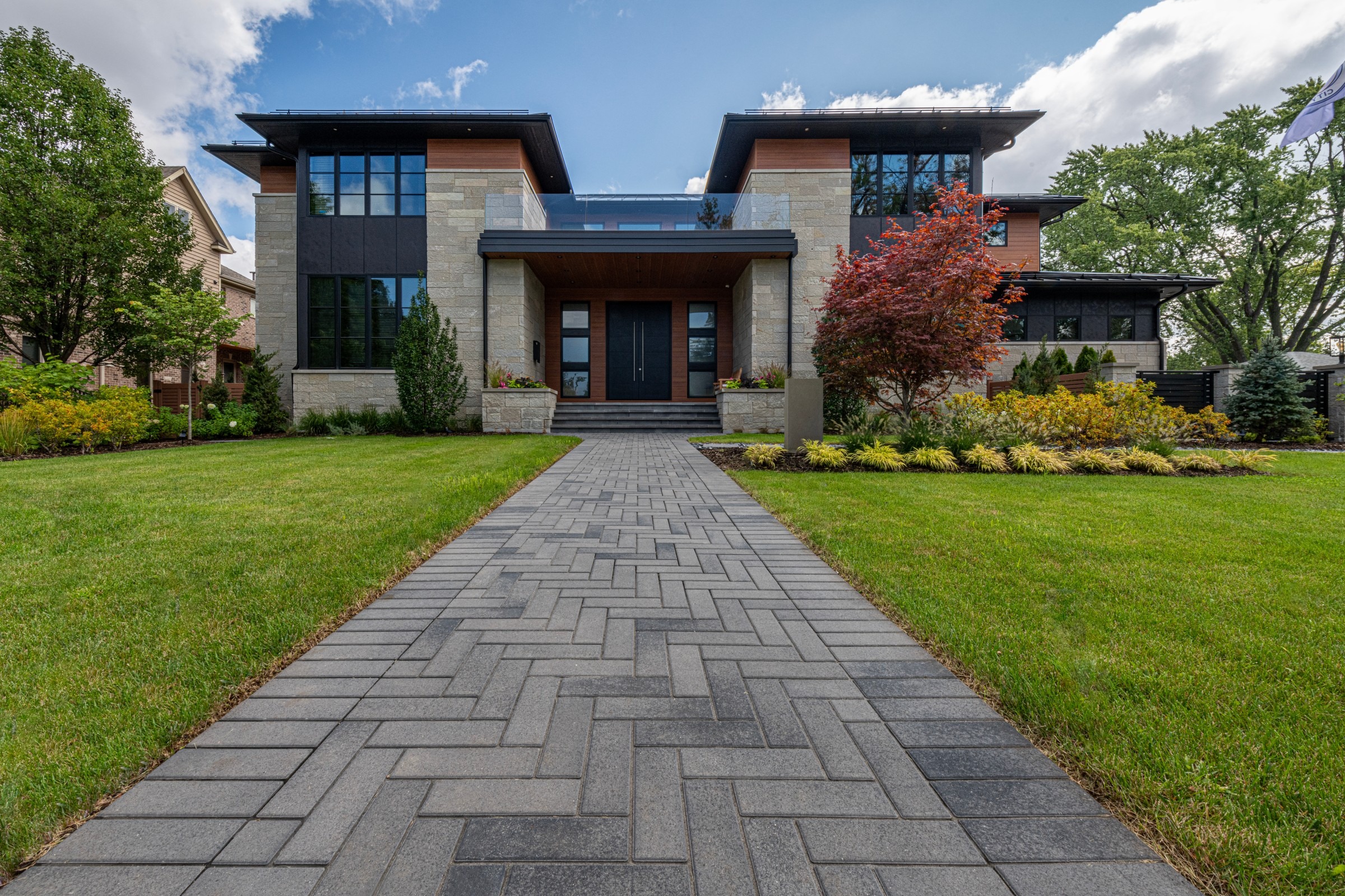 Front yard with modern walkway, evergreens, and ornamental trees showing four-season landscape design.