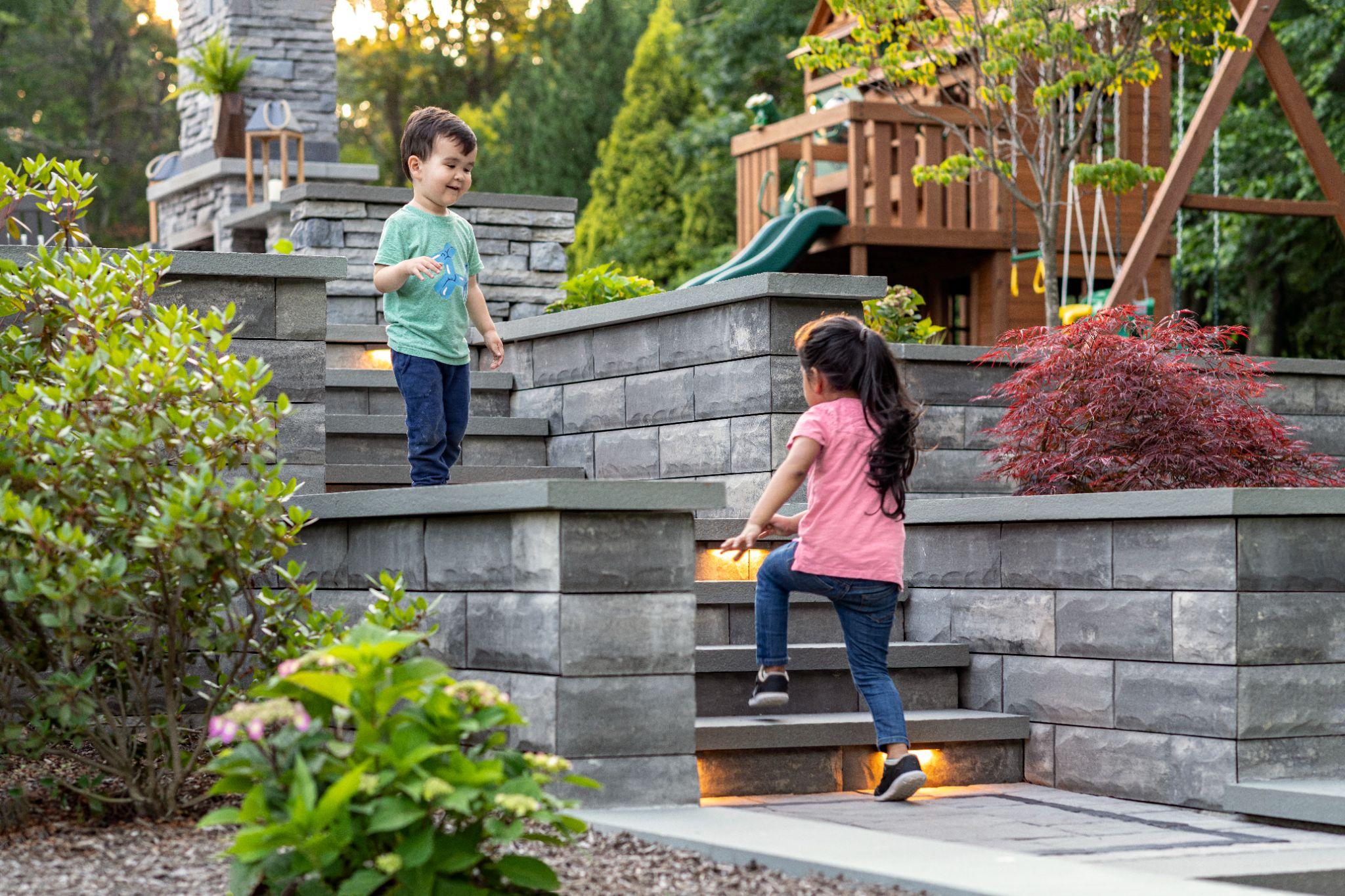 Children playing on tiered concrete retaining wall steps