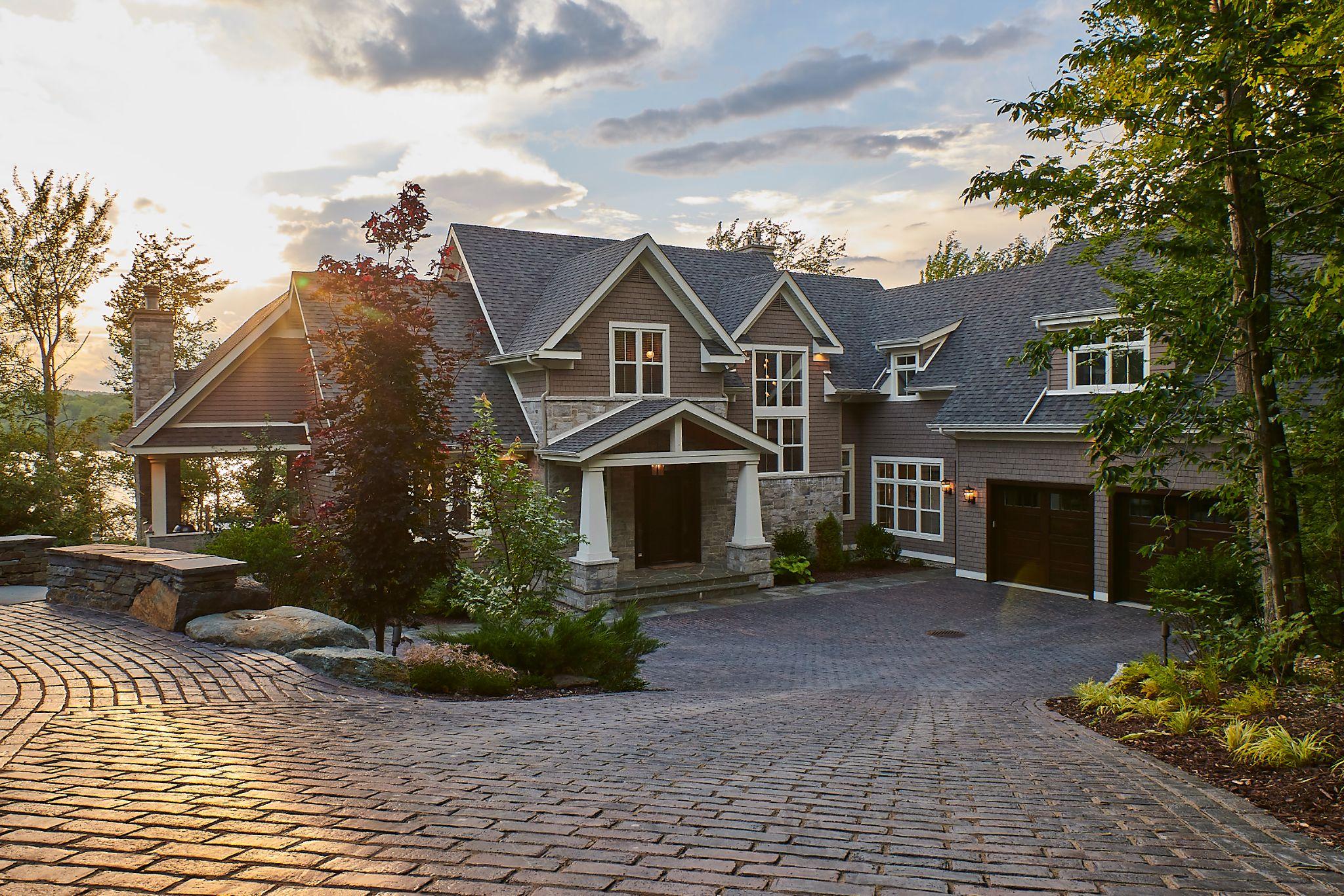 Elegant brick driveway leading to luxury home at sunset