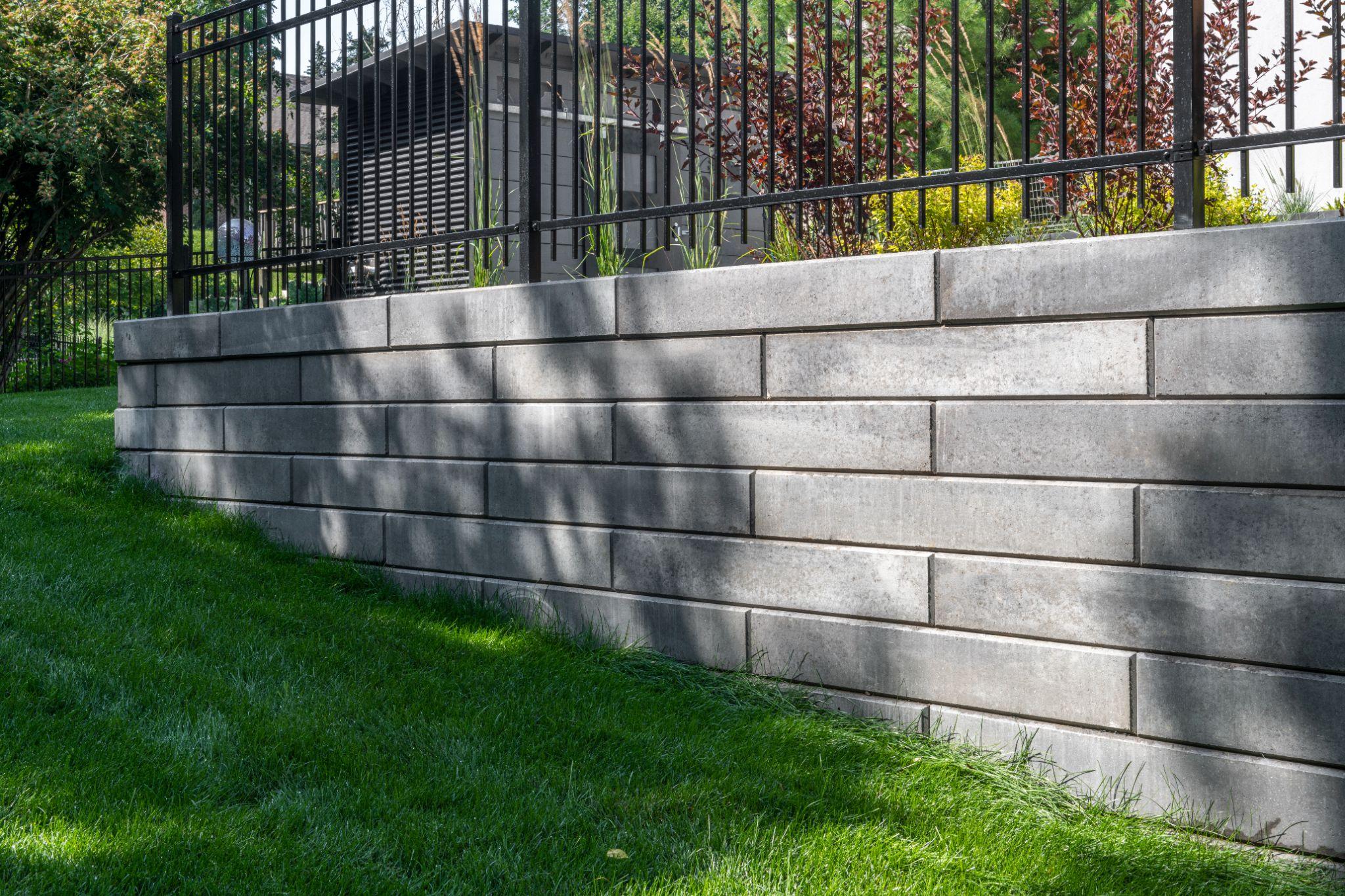 Linear concrete retaining wall with metal fence