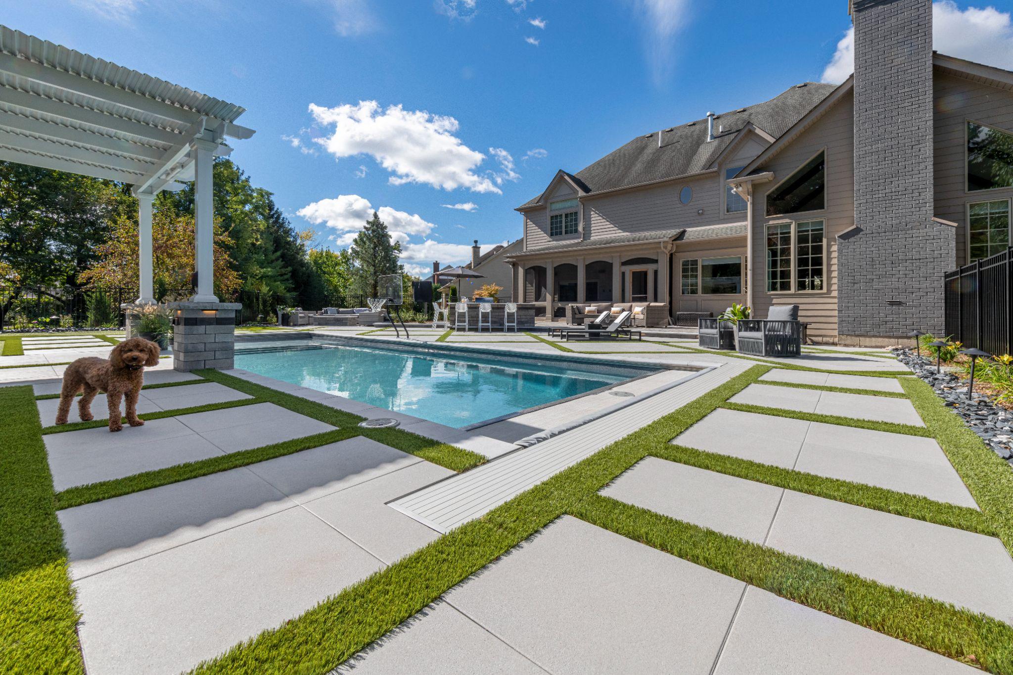 Modern backyard pool patio with large concrete slabs and turf joints