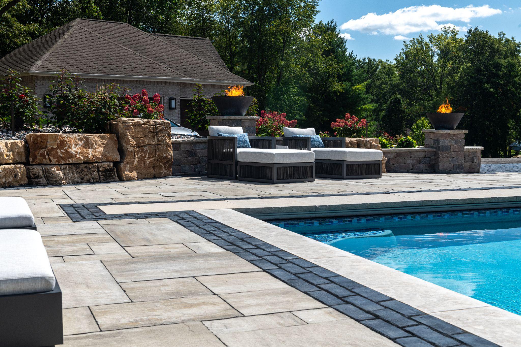 Modern poolside patio with large stone pavers and fire features